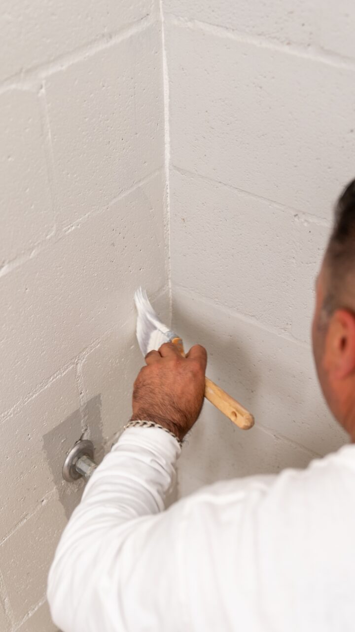 A person painting a white wall in the corner of a room with a paintbrush, transforming it as part of the Lookout Project at Wentworth Falls.