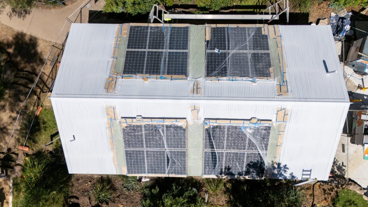 Aerial view of a white building with solar panels on its roof, surrounded by greenery and construction materials from the ongoing Toilet Block Transformation project near Wentworth Falls Lookout.